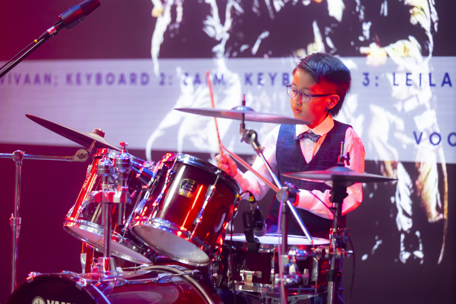 A young learner performing drums on stage